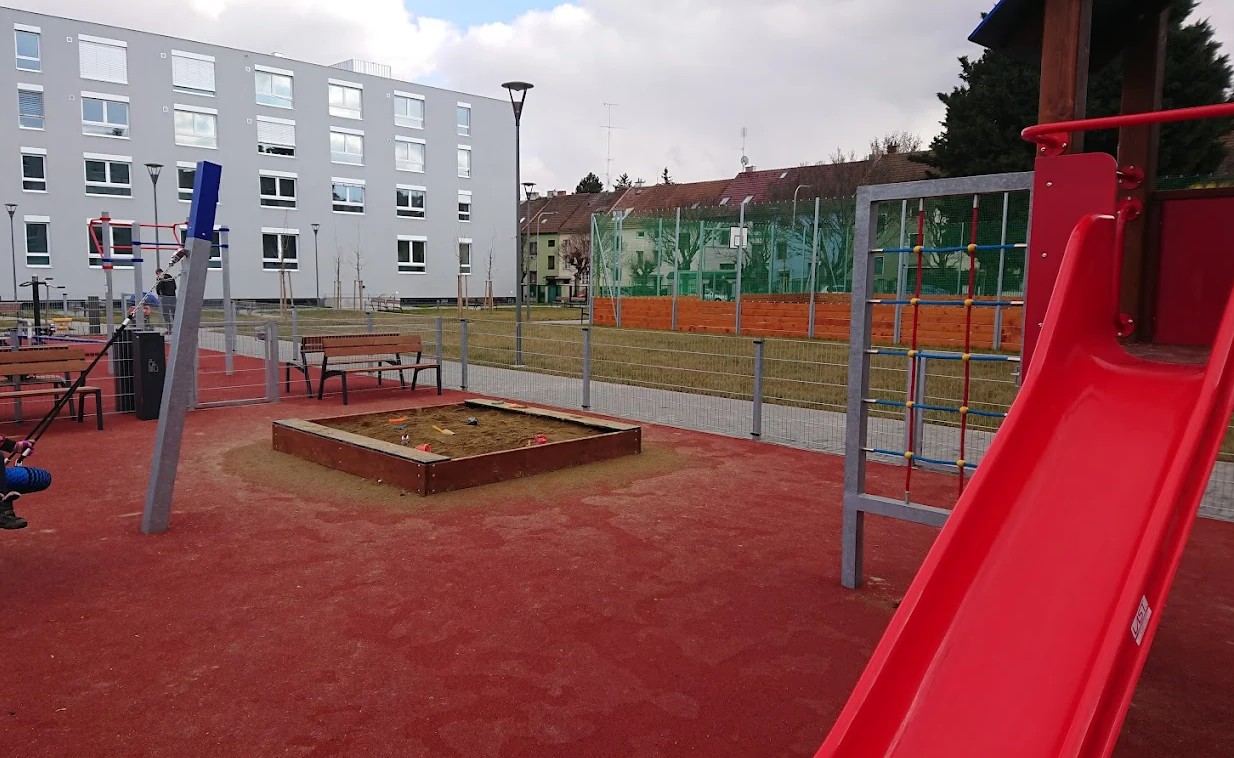 Eingezäunter Spielplatz mit Rutsche und Sandkasten